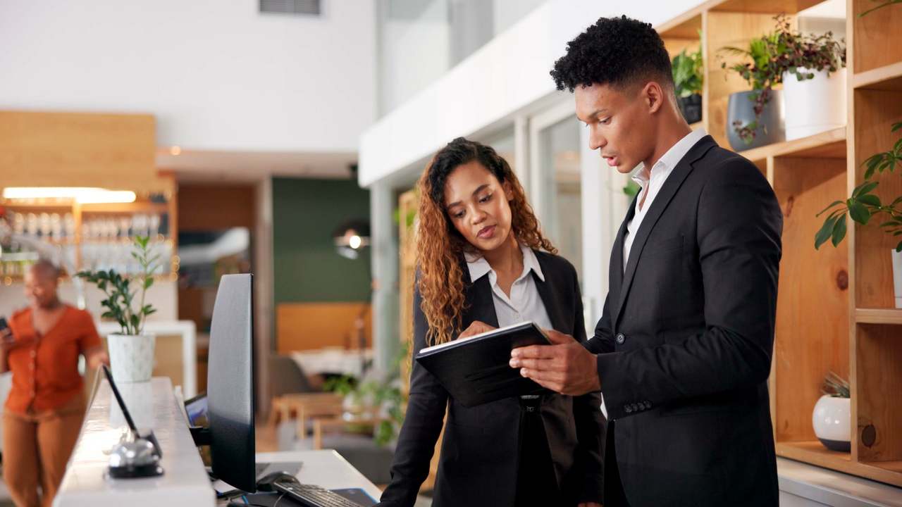 two hospitality managers reviewing a document at a hotel reception counter