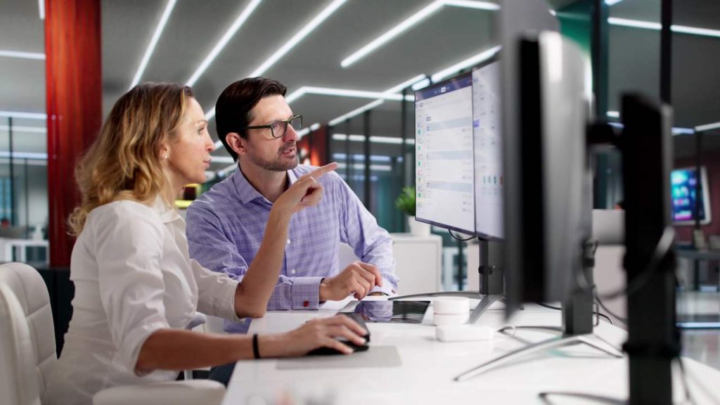 Two professionals reviewing workforce planning information on a computer in a modern office.